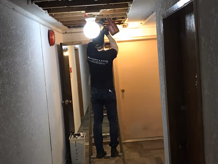 Man working through ceiling on plumbing or heating repairs. 